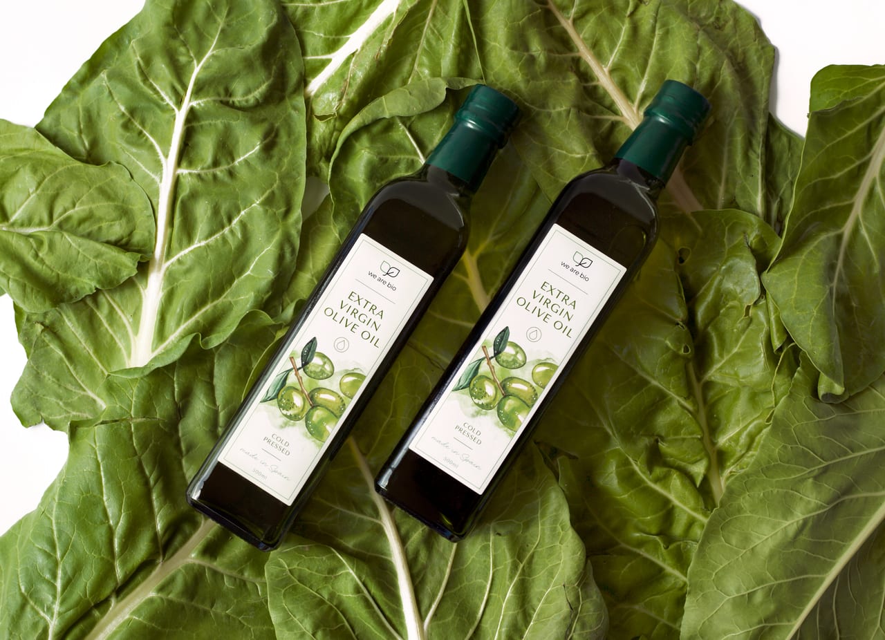 Botellas de aceite de oliva sobre hojas de acelga